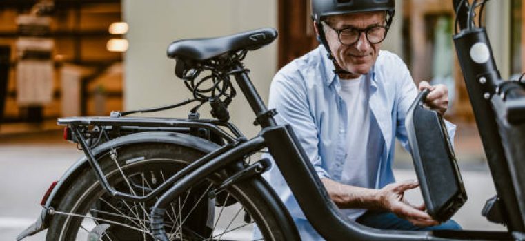 Senior man changing battery on electric bicycle